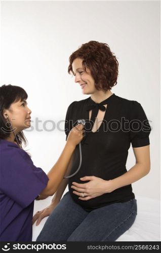 Pregnant Caucasian mid-adult woman having vital signs checked by nurse.