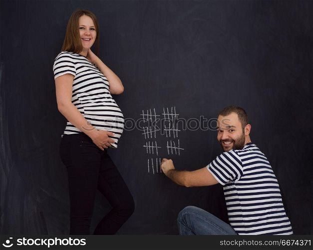 pregnant couple accounts week of pregnancy. young pregnant couple accounts week of pregnancy and writing them with chalk on blackboard