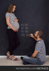 pregnant couple accounts week of pregnancy. young pregnant couple accounts week of pregnancy and writing them with chalk on blackboard
