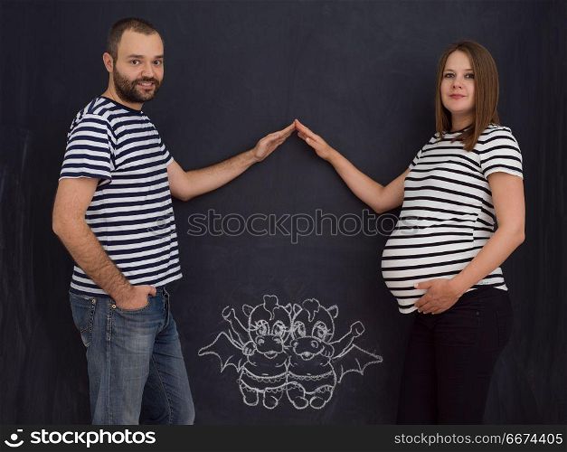 pregnant couple drawing their imaginations on chalk board. Conceptual photo of pregnant couple drawing their imaginations about the future life with children on chalk board