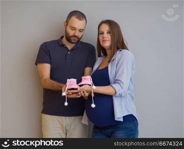 pregnant couple holding newborn baby shoes. young pregnant couple holding newborn baby shoes isolated on white background in family and parenthood concept