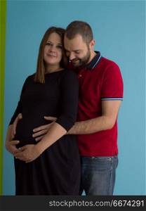 pregnant couple isolated over blue background. Portrait of a happy young couple,man holding his pregnant wife belly isolated over blue background