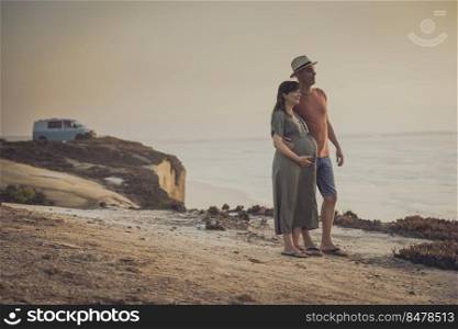 Pregnant couple on a wild beach and their dog expecting a baby