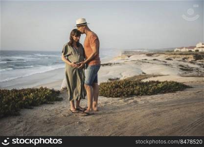 Pregnant couple on a wild  beach expecting a baby