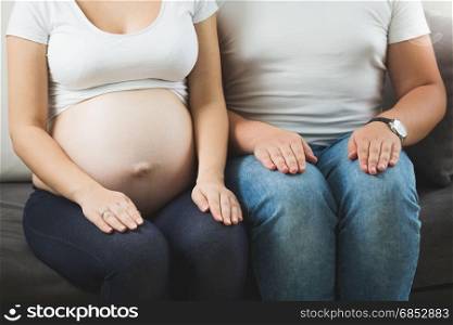 Pregnant couple sitting on sofa next to each other