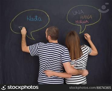 pregnant couple writing on a black chalkboard. young pregnant couple thinking about names for their unborn baby and writing them on a black chalkboard