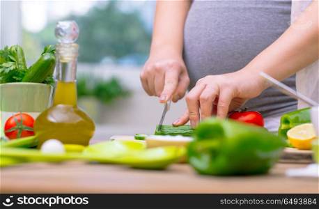 Pregnant female cutting fresh vegetables for salad at home, body part, vitamins and organic food for future mother, healthy lifestyle in pregnancy period. Organic nutrition for pregnant woman