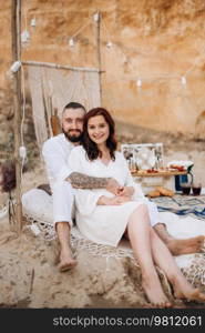 pregnant girl and boyfriend on a picnic by the sea in white clothes