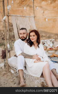 pregnant girl and boyfriend on a picnic by the sea in white clothes