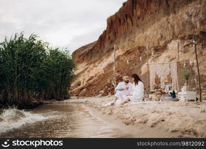 pregnant girl and boyfriend on a picnic by the sea in white clothes