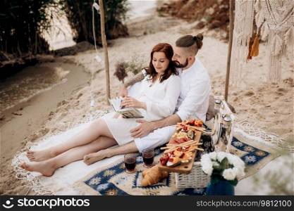 pregnant girl and boyfriend on a picnic by the sea in white clothes