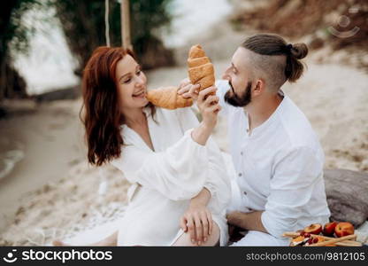 pregnant girl and boyfriend on a picnic by the sea in white clothes