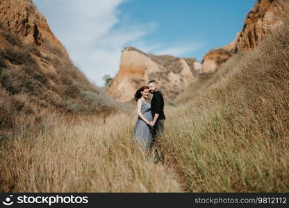 pregnant girl and boyfriend on high hills near the sea