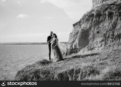 pregnant girl and boyfriend on high hills near the sea