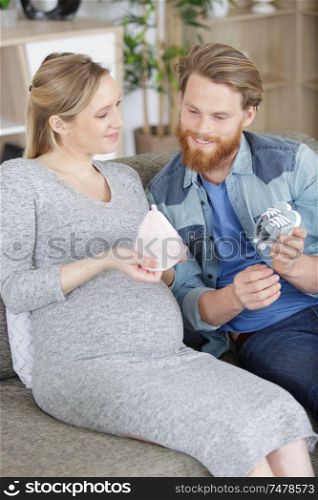 pregnant happy couple with baby accessories