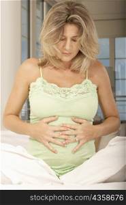 Pregnant mid adult woman touching her abdomen