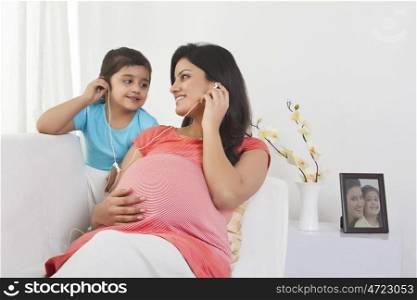 Pregnant mother and daughter listening to music