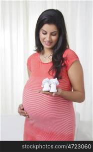 Pregnant mother holding baby shoes