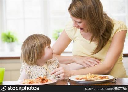 Pregnant mother with daughter touching belly eating French fries and pizza