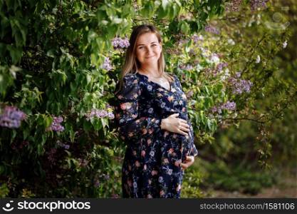 pregnant woman among the flowers. enjoys the beauty of spring among the flowering trees.Reuniting with nature in a flowering spring garden. pregnant woman among the flowers. enjoys the beauty of spring among the flowering trees.Reuniting with nature in a flowering spring garden.