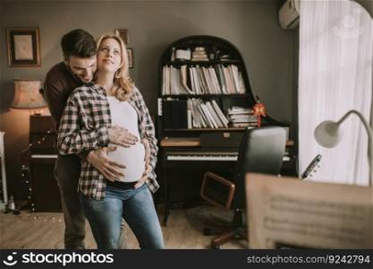 Pregnant woman and happy man in the house standing hugged in the room