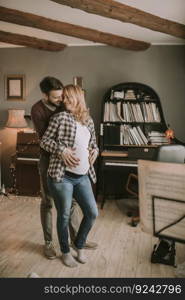 Pregnant woman and happy man in the house standing hugged in the room