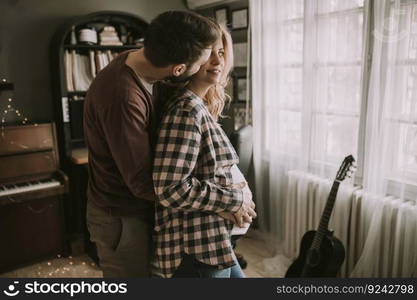 Pregnant woman and happy man in the house standing hugged in the room