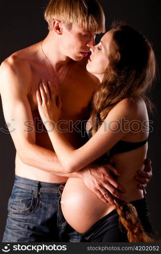 pregnant woman and her man on black background