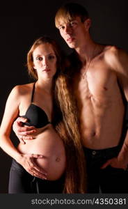 pregnant woman and her man on black background