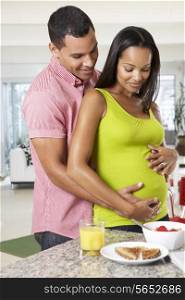 Pregnant Woman And Husband Having Breakfast In Kitchen