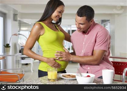Pregnant Woman And Husband Having Breakfast In Kitchen