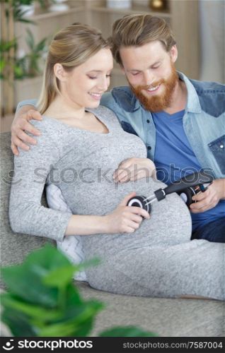 pregnant woman and husband holding headphones on tummy