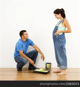 Pregnant woman and husband preparing to paint interior home wall.
