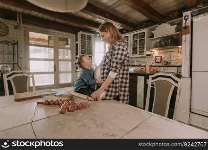 Pregnant woman and little daughter in the rustic kitchen preparing meal