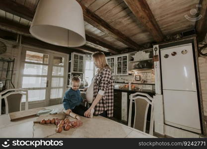 Pregnant woman and little daughter in the rustic kitchen preparing meal