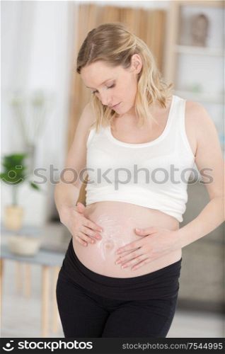 pregnant woman applying cream to belly