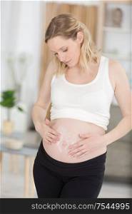 pregnant woman applying cream to belly