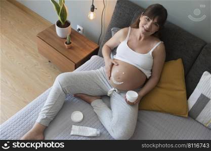 Pregnant woman applying stretch mark cream in her belly