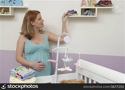 Pregnant woman arranging things in baby room