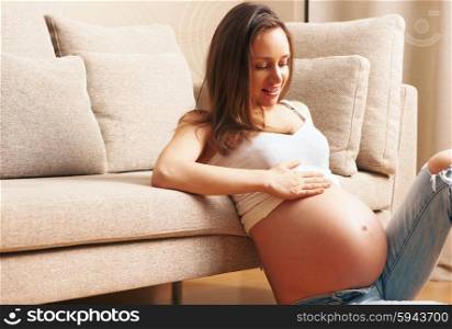 Pregnant woman at home sitting by the couch
