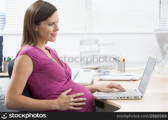 Pregnant woman at work using laptop