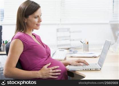Pregnant woman at work using laptop