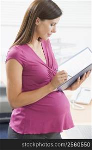 Pregnant woman at work writing in binder