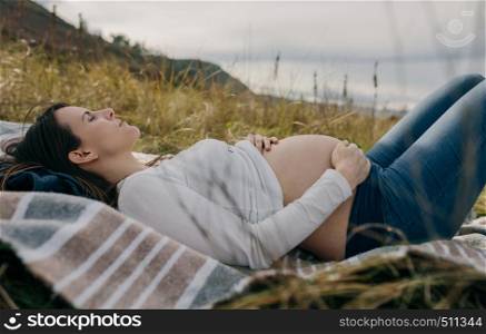 Pregnant woman caressing her naked tummy sleeping on the grass. Pregnant woman caressing her tummy sleeping