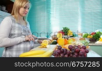 Pregnant woman cutting a lemon in the kitchen