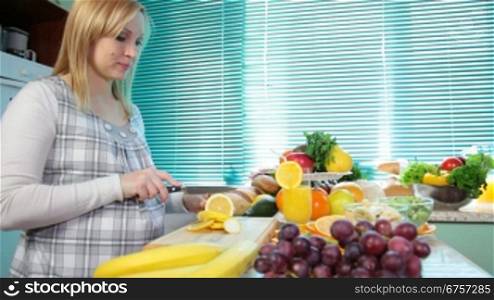 Pregnant woman cutting a lemon in the kitchen