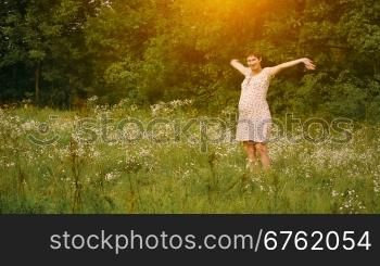 Pregnant woman dancing in the field at sunset