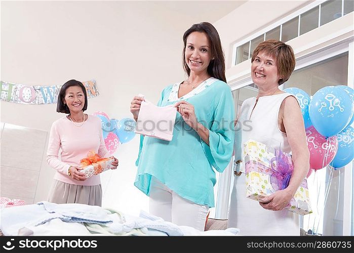 Pregnant woman displaying new gift at baby shower