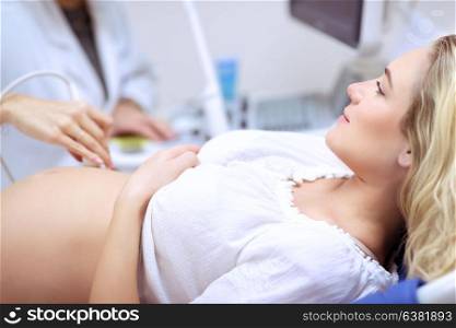 Pregnant woman doing ultrasound scan in the prenatal clinic, mother worried about health of her future baby, happy pregnancy time