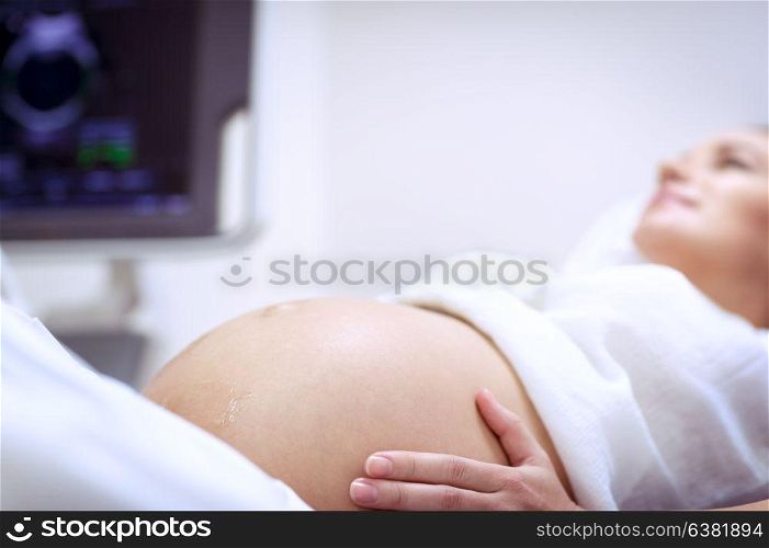Pregnant woman doing ultrasound scanning in the prenatal clinic, mother checking health of her future baby, happy pregnancy time